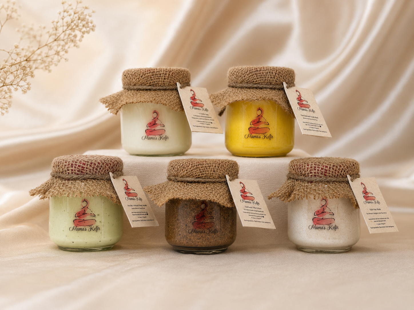 Five Mama's Kefir jars with burlap tops and hand-tied tags on cream silk